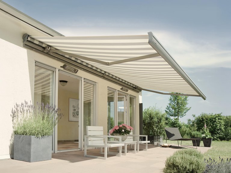 Markise über einer Terrassensituation mit Pflanzen in Kübeln und einer Überdachung im Hintergrund.