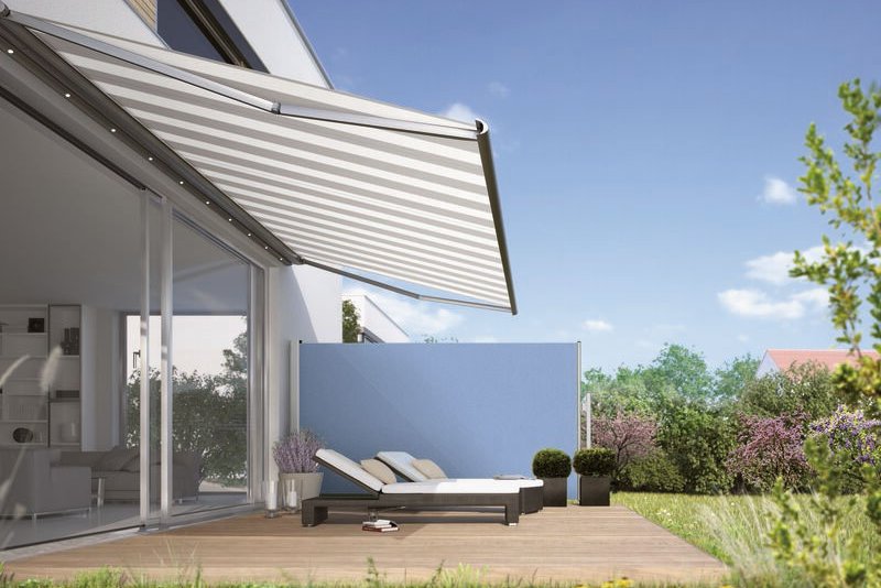 Sonnenschutz in Form einer Markise über einer Terrassensituation mit Liegen und grüner Umgebung.