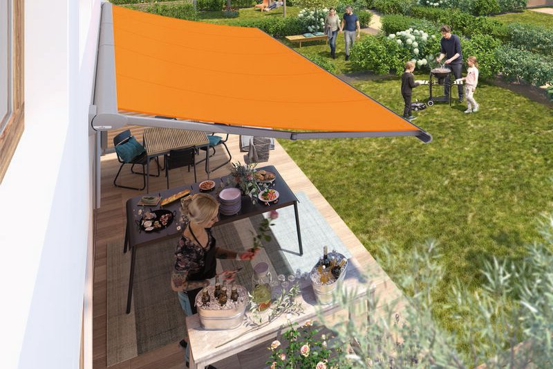 Terrassensituation mit orangefarbener Markise und gedecktem Tisch im Garten mit Grünflächen und Aktivitäten.