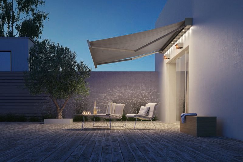 Sonnenmarkise in einem modernen Terrassensituation mit Holzfußboden und Bäumen im Hintergrund.
