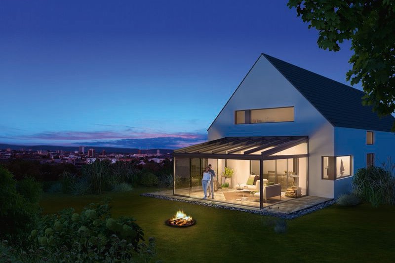 Ein modernes Haus mit Glas-Schiebewänden, umgeben von Grün, am Abend mit blauen Himmel und einem Feuerplatz im Vordergrund. Ein modernes Haus mit Glas-Schiebewänden, umgeben von Grün, am Abend mit blauen Himmel und einem Feuerplatz im Vordergrund.