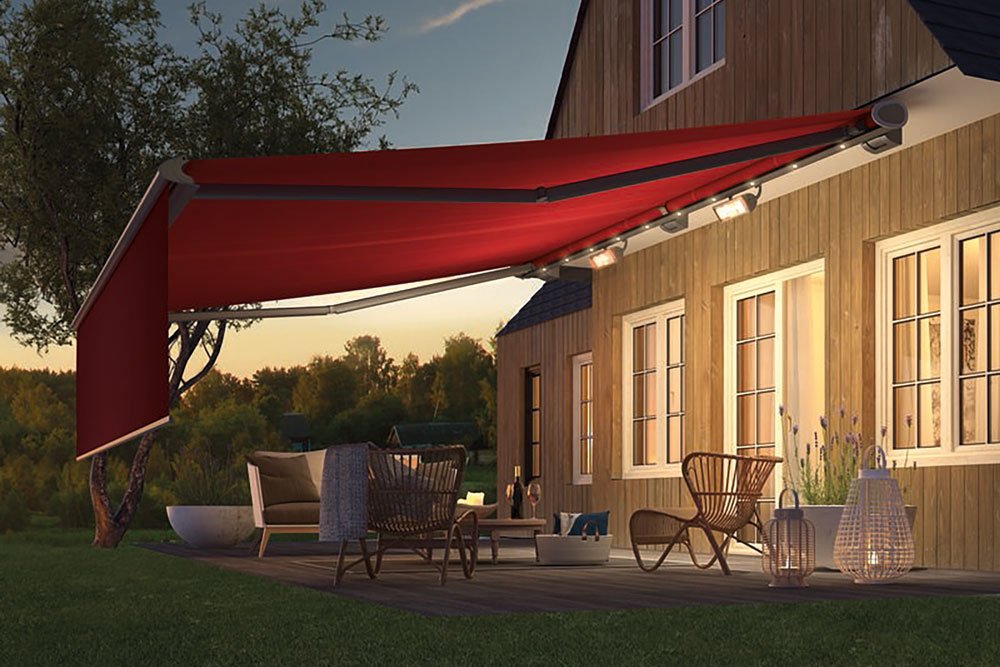 Terrassensituation mit roter Markise an einem Holzhaus, umgeben von Grün.