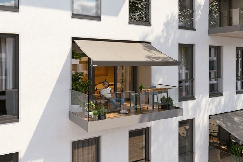 Moderne Fassade mit Balkon und Markise, große Fenster und Glasgeländer, minimalistische Architektur.
