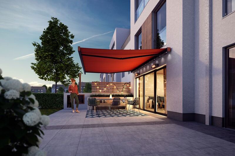 Sonnenschutz in Rot über einer modernen Terrassensituation mit Sitzbereich und Pflanzen im Vordergrund.