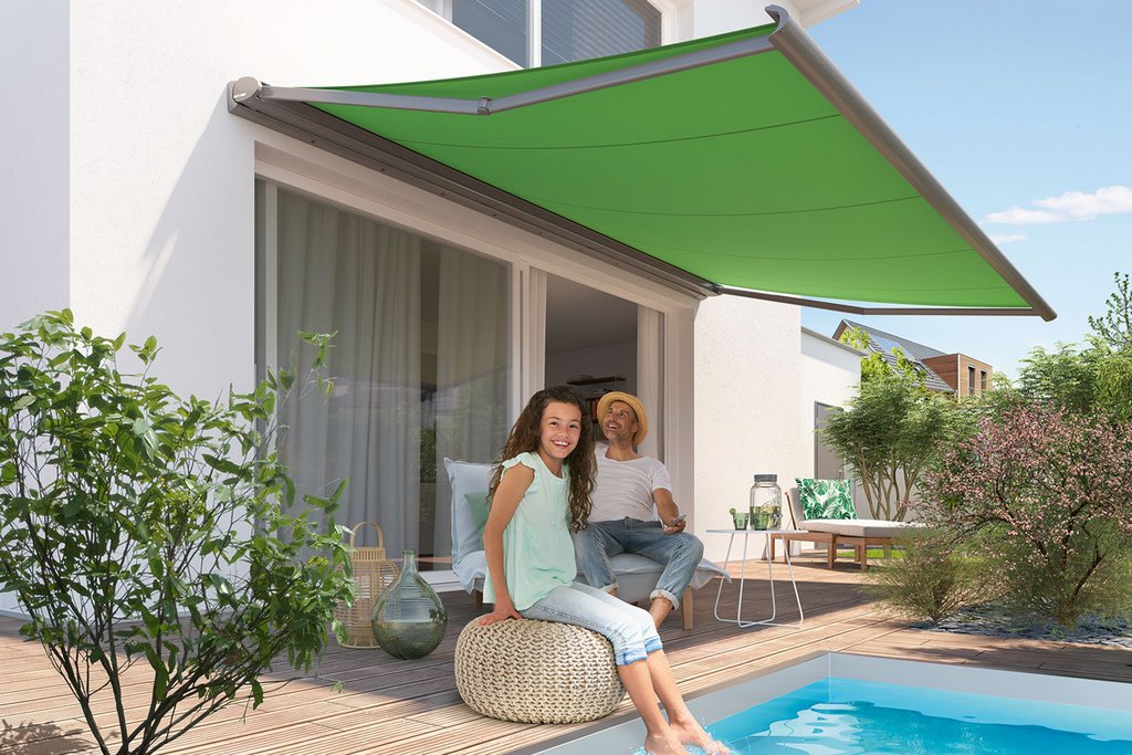 Markise in leuchtendem Grün über einem Pool, zwei Personen entspannen auf einer Terrasse.