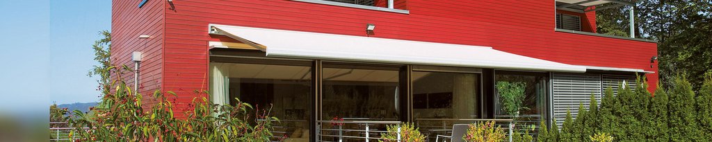 Moderne Architektur mit roter Fassade und Überdachung, umgeben von grünen Pflanzen und Terrassensituation. Moderne Architektur mit roter Fassade und Überdachung, umgeben von grünen Pflanzen und Terrassensituation.